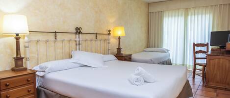 Una habitación de hotel con una cama grande, dos mesitas de noche con lámparas, un aparador de madera, una silla y un televisor.