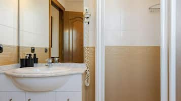 A bathroom with a sink, mirror, and shower.