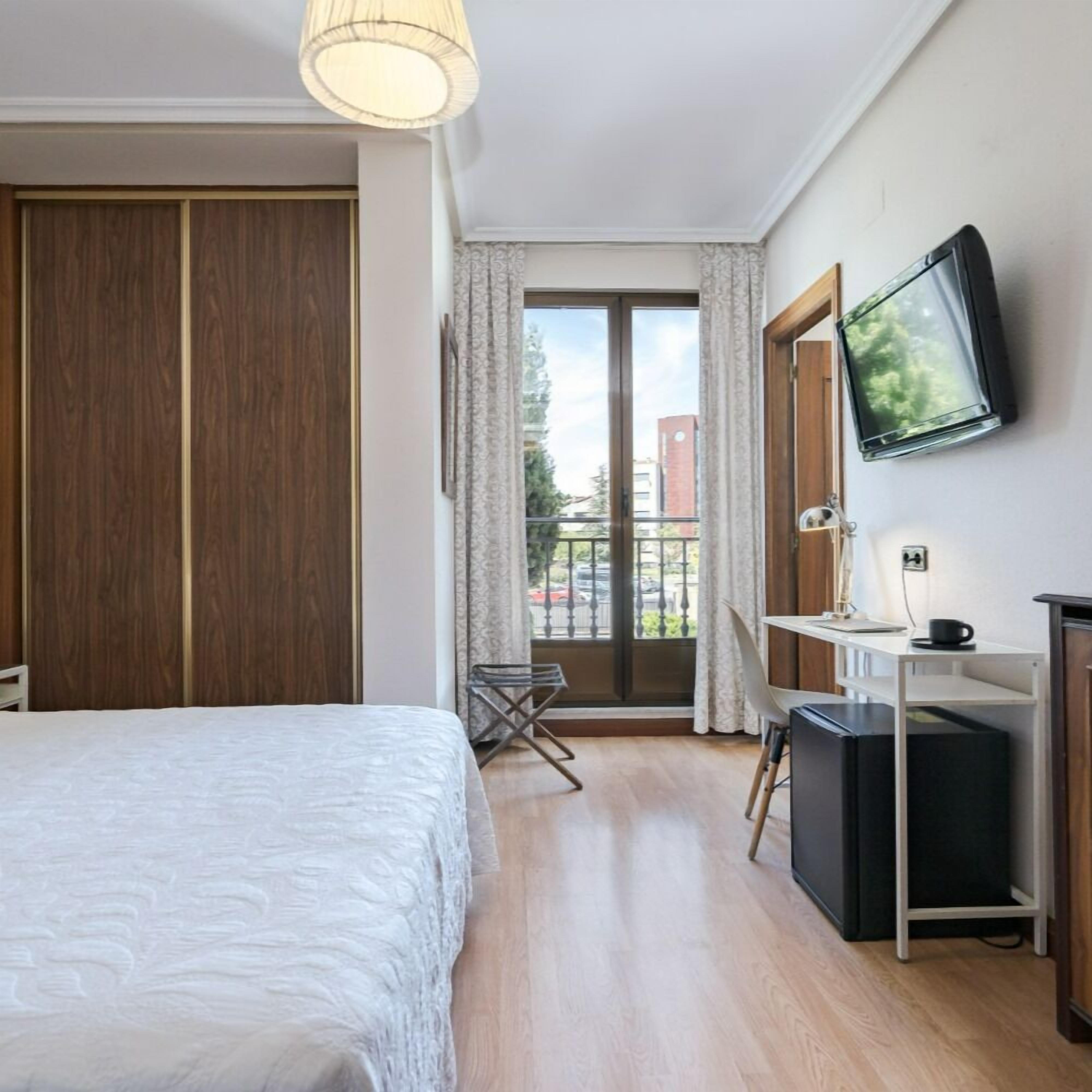 Une chambre d’hôtel avec un lit, un bureau équipé d’un ordinateur, une télévision et une vue sur l’extérieur.