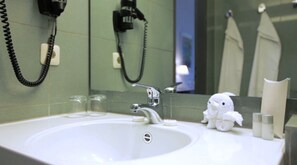 A bathroom sink with a mirror, two glass tumblers, a white plush toy, and a telephone. - Aussen Alster Hotel (Hamburg)