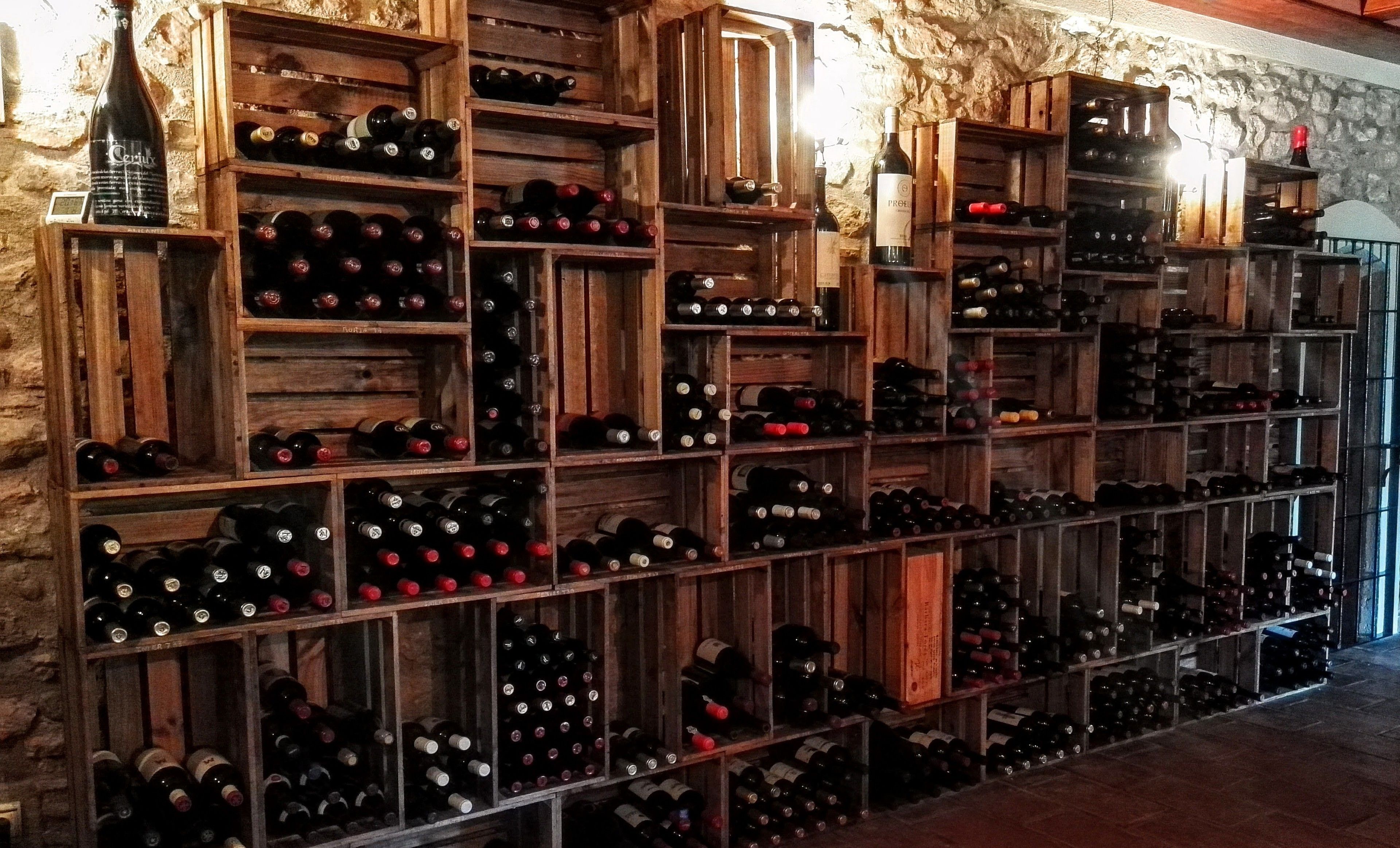 Una bodega con estantes de madera llenos de botellas de vino.