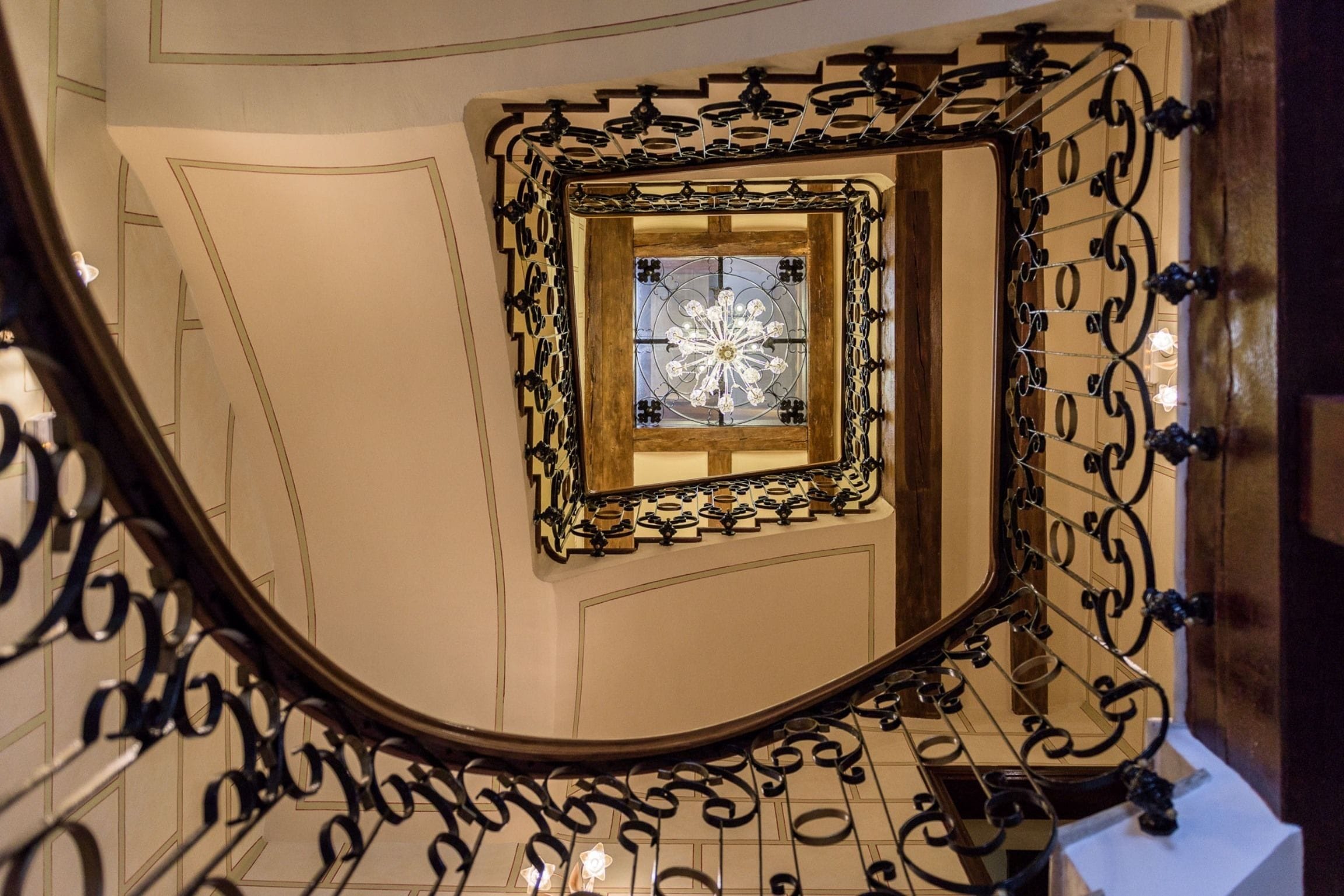 A curved staircase with ornate black metal railings and a wooden handrail.
