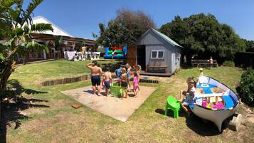 Children can play on the inflatable slide and boat-shaped play structure in the grassy lawn.