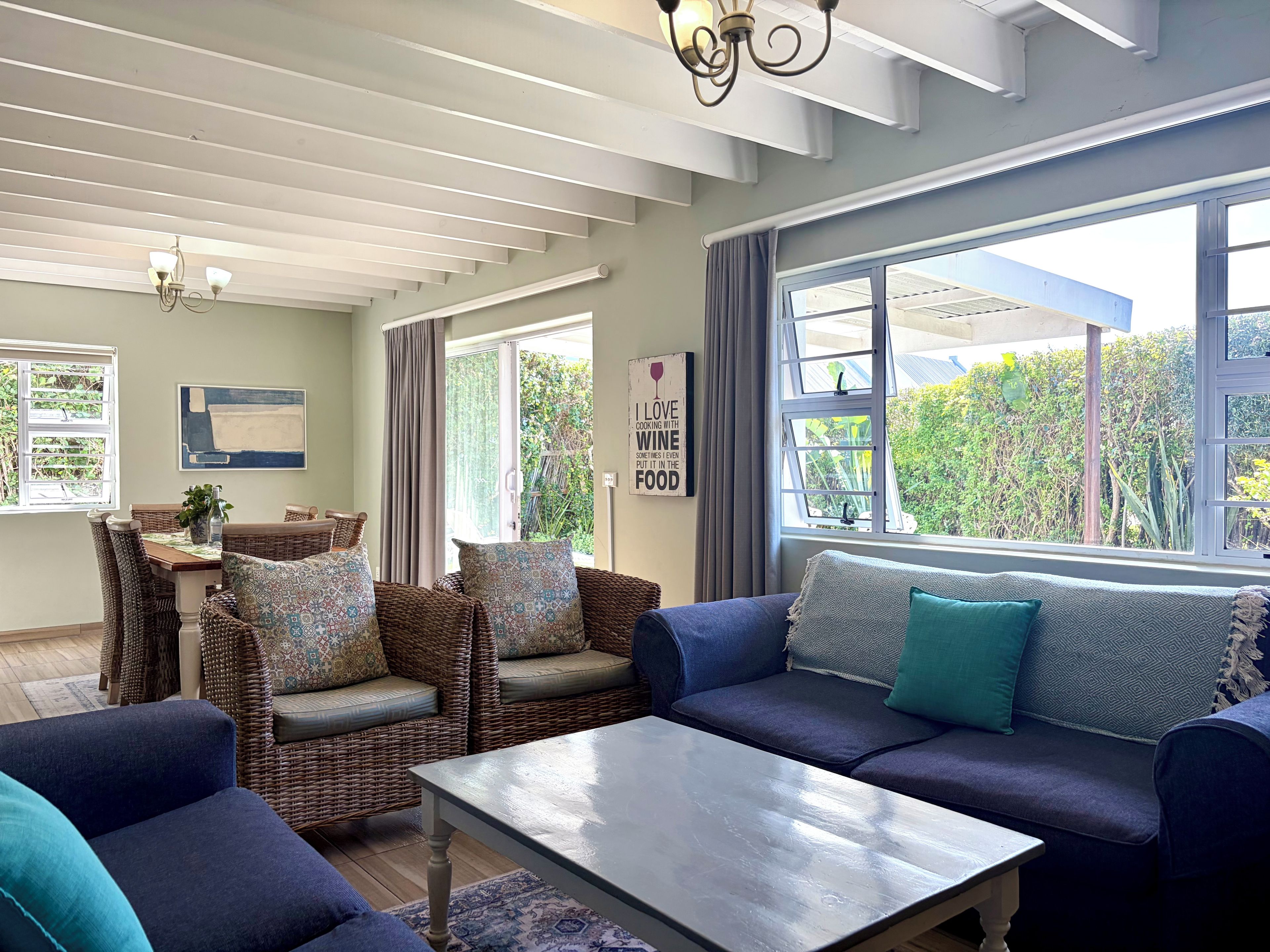 A modern living room with a sofa, chairs, and a dining table.