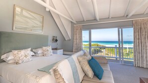 Een slaapkamer met een groot bed, een bank en een balkon met uitzicht op zee.
