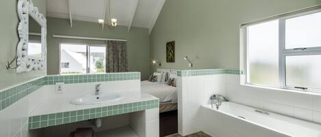 A modern bathroom with a large window, a white sink, a bathtub, and a mirror.