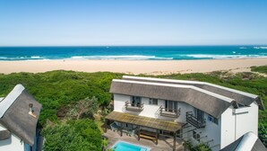 Een modern huis met zwembad, met uitzicht op een strand en oceaan.