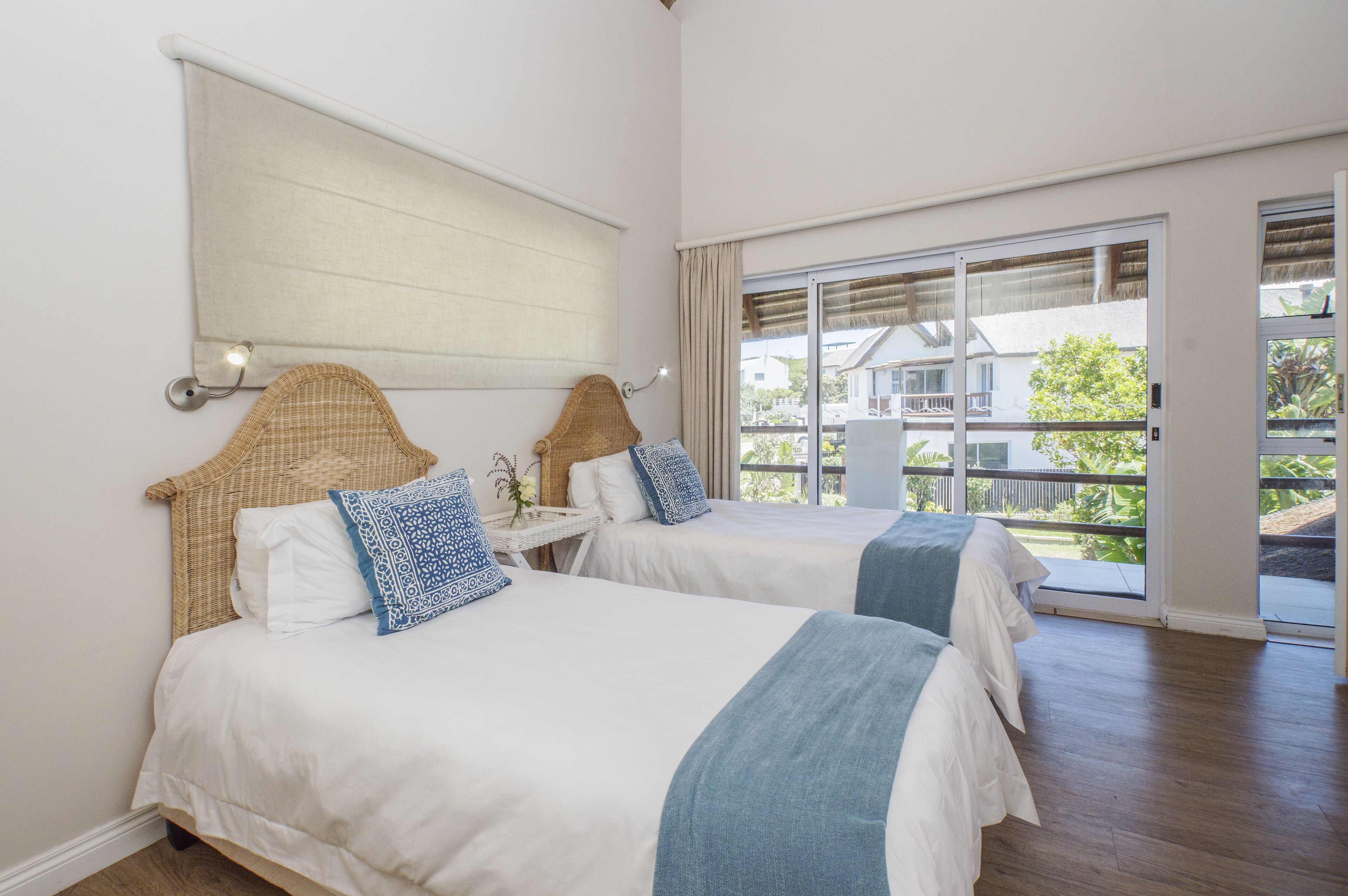A hotel room with two beds, a large window, and a view of the outside.