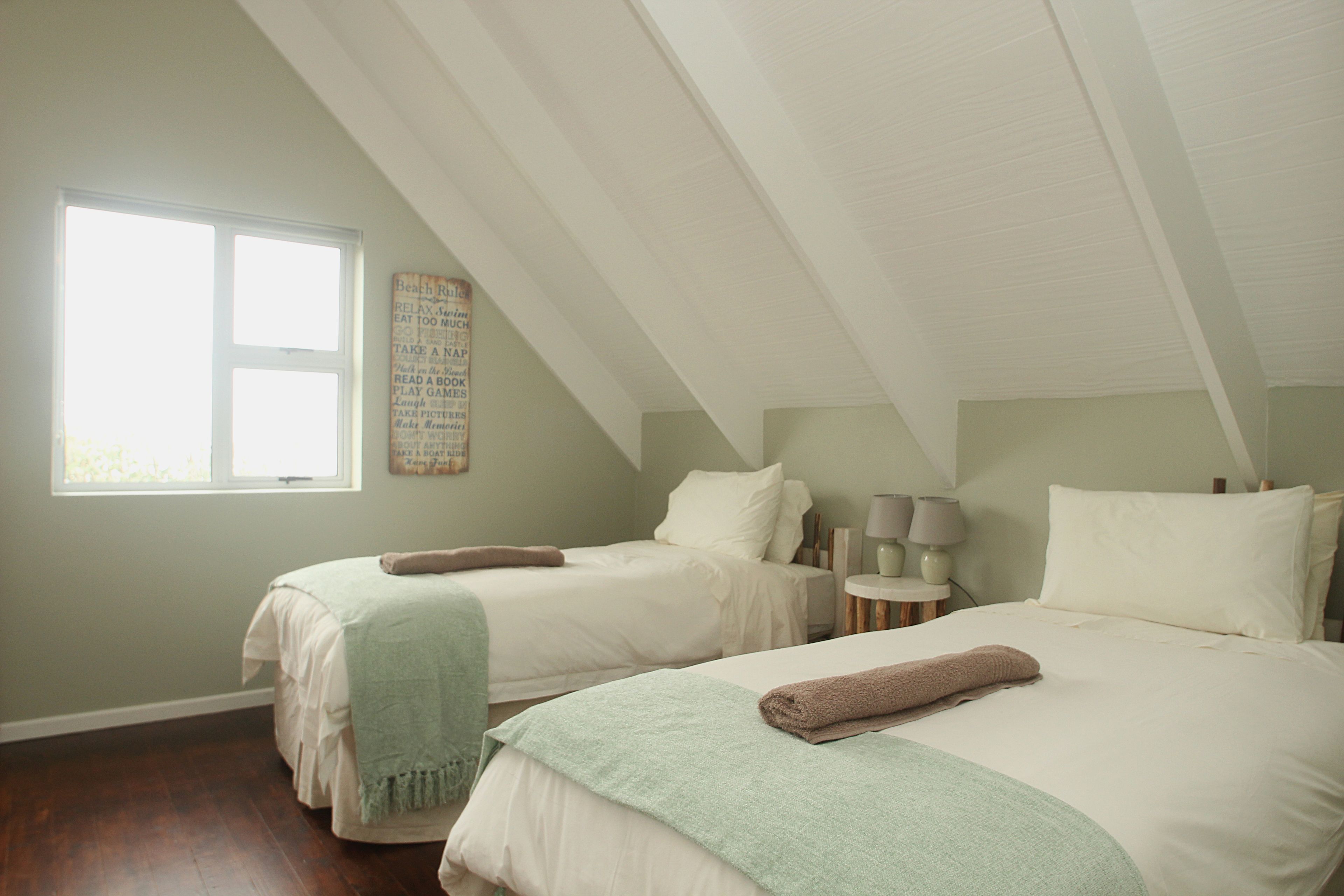 A bedroom with two beds, a window, and a wall with a decorative piece.