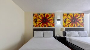 A hotel room with two beds, a nightstand with a lamp, and two large floral paintings on the wall. - Hotel Valle de Mexico Toreo (Naucalpan)