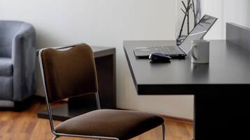 Una silla de oficina moderna con estructura metálica y asiento acolchado, sobre piso de madera.