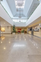 A spacious lobby with a high ceiling, a reception desk, and a modern chandelier.
