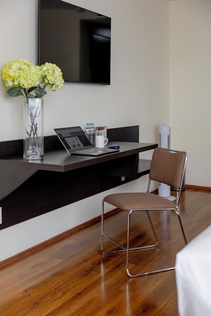 A modern office space with a desk, chair, laptop, and a flat-screen TV mounted on the wall.
