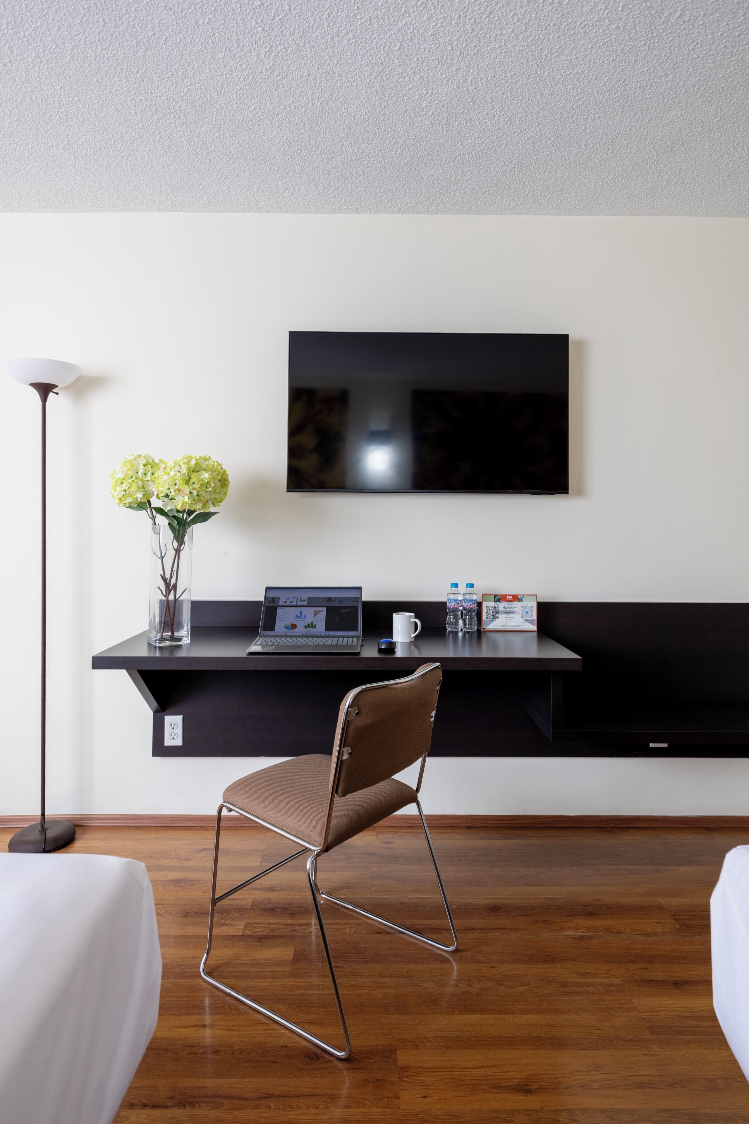 Una habitación moderna con escritorio, silla y televisor de pantalla plana montado en la pared.