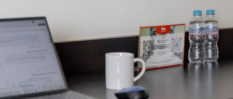 Un escritorio con una computadora portátil, una taza blanca, una botella de agua y un documento impreso.