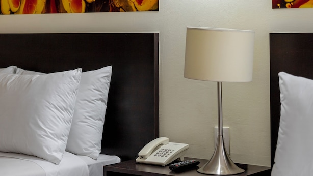 A hotel room with a bed, a bedside table with a lamp, a phone, and artwork on the wall. - Hotel Valle de Mexico Toreo (Naucalpan)