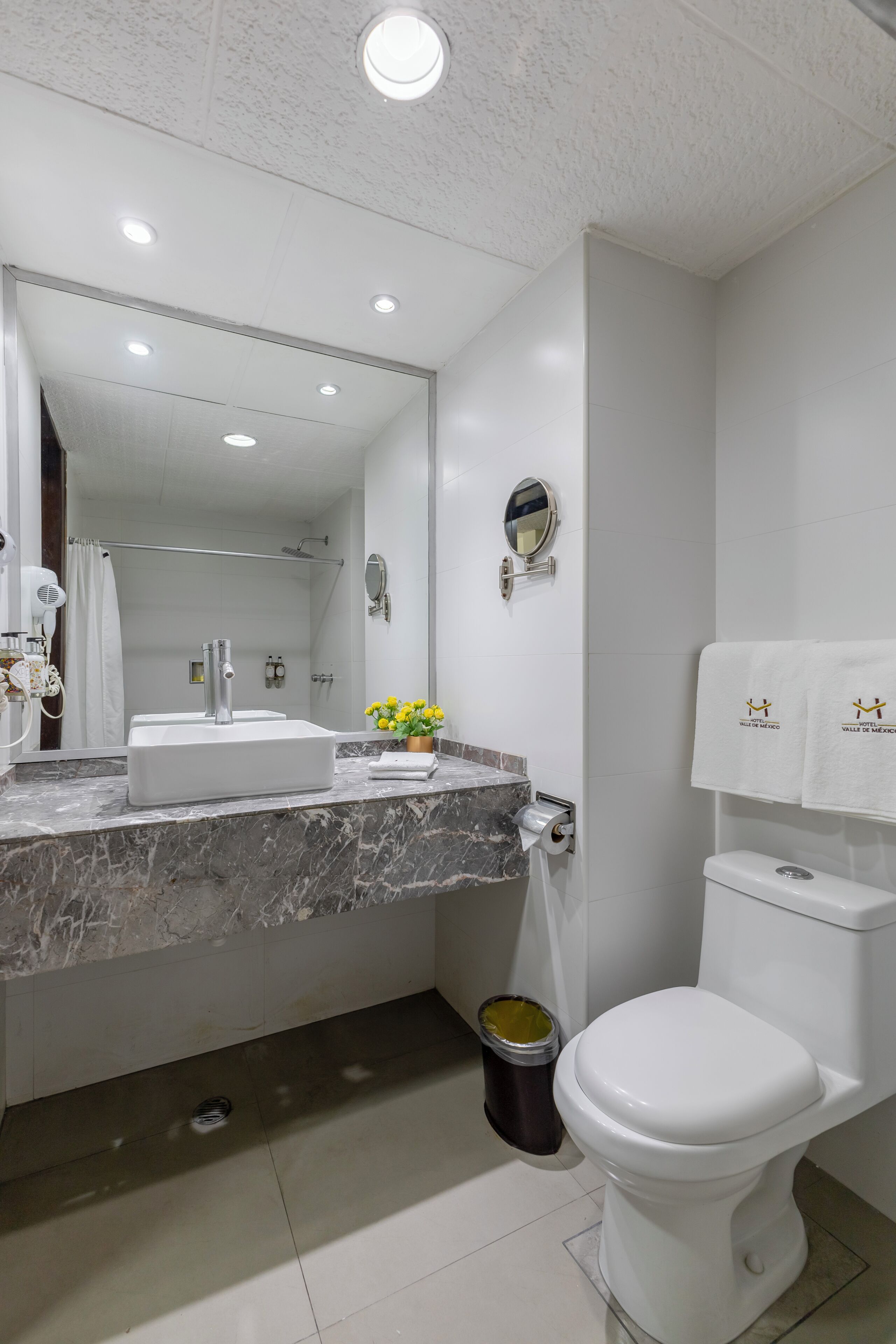 A modern bathroom with a white sink, mirror, and toilet.