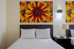 A hotel room with a bed, white pillows, a nightstand with a lamp, a phone, and a wall-mounted light. - Hotel Valle de Mexico Toreo (Naucalpan)