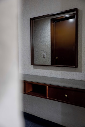 Un mueble de pared con espejo y un cajón pequeño.