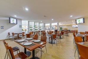 A spacious dining area with multiple tables and chairs, equipped with flat-screen TVs on the walls. - Hotel Valle de Mexico Toreo (Naucalpan)