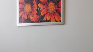 A dark grey armchair in a room with a wooden floor and a framed painting of orange flowers on the wall.