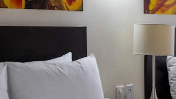 A hotel room with a bed, a nightstand, a lamp, a phone, and a wall with abstract art.