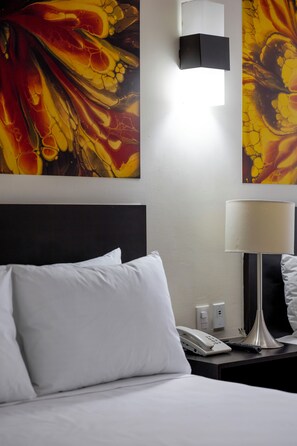 A hotel room with a bed, a nightstand, a lamp, a phone, and a wall with abstract art. - Hotel Valle de Mexico Toreo (Naucalpan)