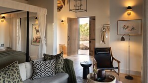 Una habitación amplia con una cama, un sofá, una silla y un comedor. Hay cuadros en las paredes y una ventana con cortinas.