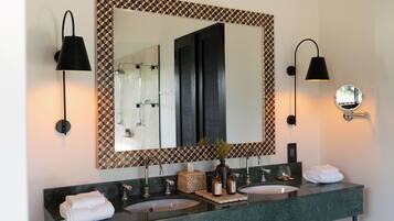 A bathroom with two sinks, a large mirror with a geometric frame, and wall-mounted lighting.