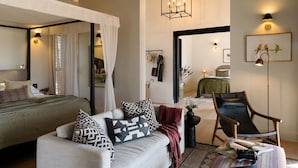 Un dormitorio con cama, sofá, sillón y espejo.