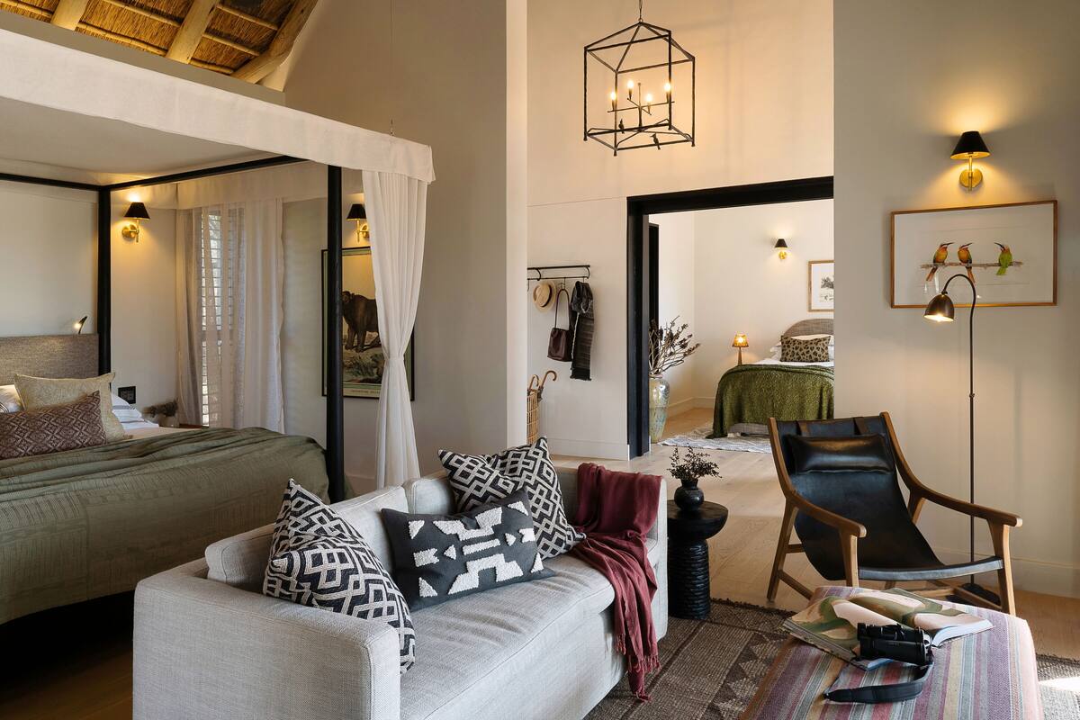 A bedroom with a bed, a sofa, a chair, and a mirror.