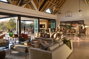 A spacious living area with a fireplace, comfortable seating, and a view of the outdoors. - Monwana (Hoedspruit)