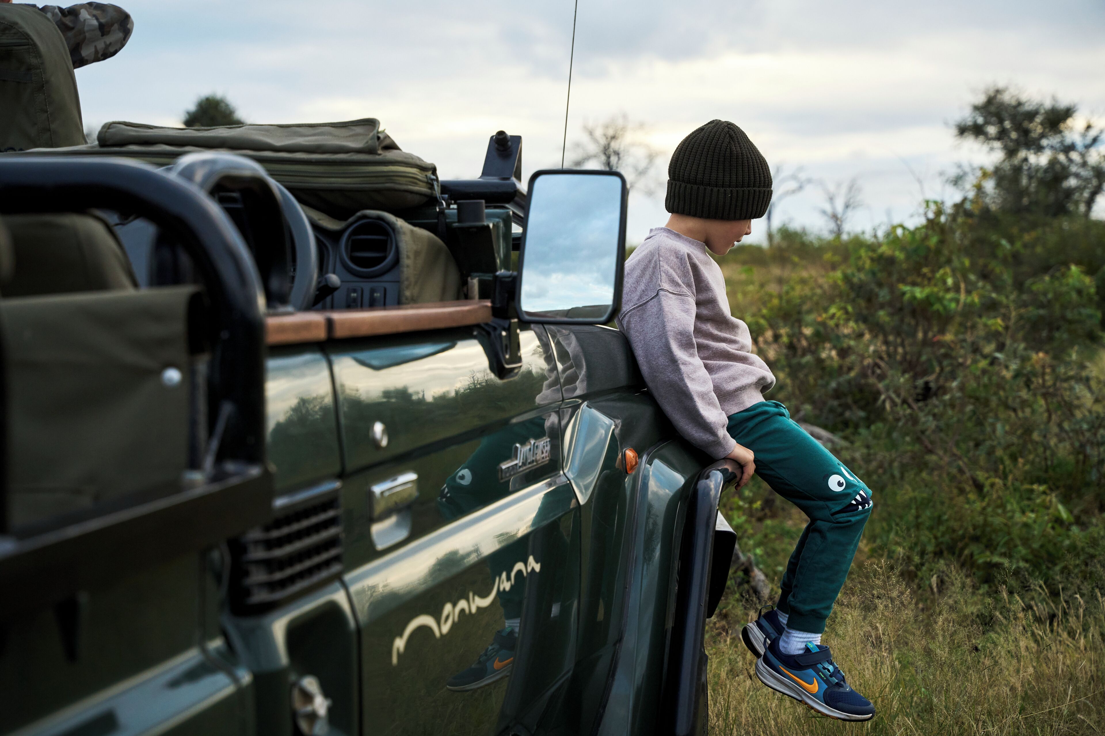 A child sitting on the side of a vehicle with a camera mounted on the roof.