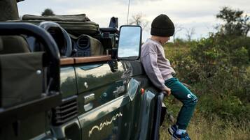 A child sitting on the side of a vehicle with a camera mounted on the roof.