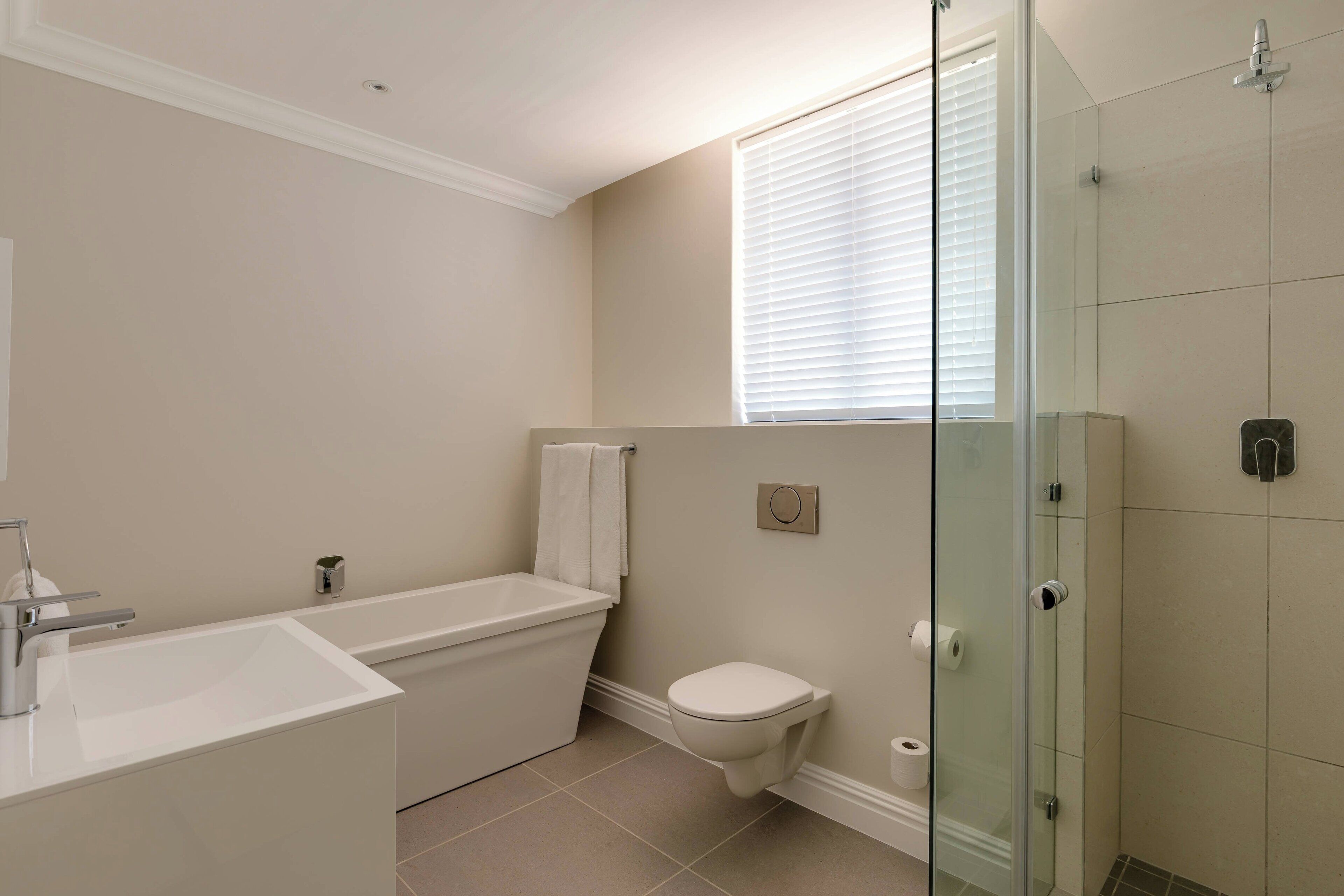 A modern bathroom with a bathtub, toilet, and glass-enclosed shower.