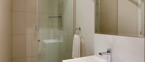 Une salle de bain moderne avec une douche à parois de verre, un lavabo blanc et un grand miroir.