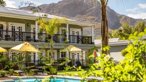 A hotel with a pool, sun loungers, and umbrellas.
