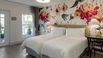 A hotel room with a large bed, a desk with a chair, and a window with curtains.