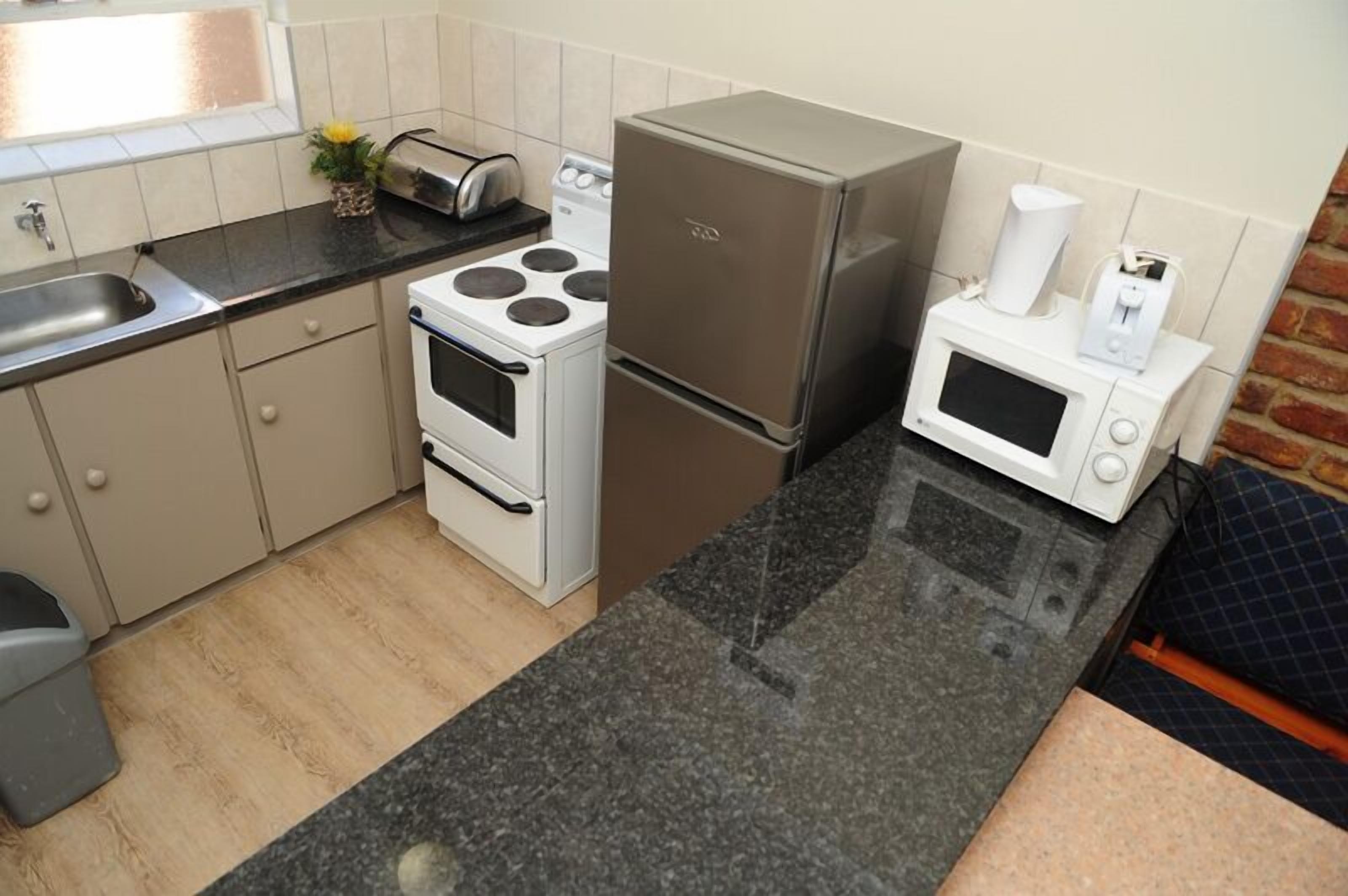 A compact kitchen with a stove, oven, refrigerator, microwave, and a sink.