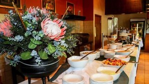 Montaje de bufé con un centro de mesa floral, varios platos de servir y una gran variedad de alimentos.