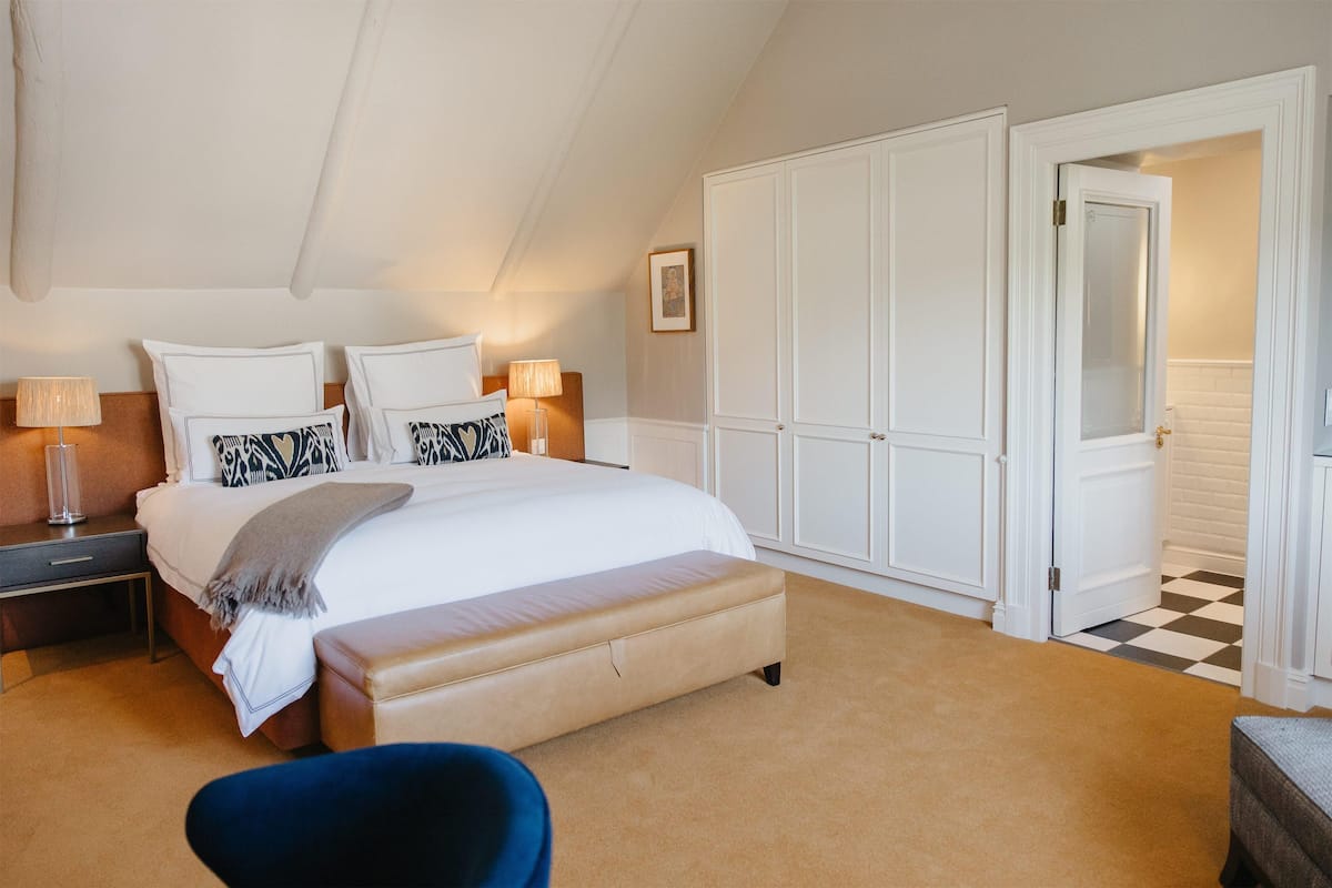A bedroom with a large bed, bedside tables, a bench, and a wardrobe.
