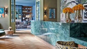 A modern lobby with a marble reception desk, a large bookshelf, and a tropical mural. - Erinvale Estate Hotel And Spa (Cape Town)