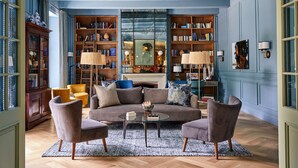 A cozy living room with a sofa, armchairs, and a fireplace. There are bookshelves filled with books and decorative items. - Erinvale Estate Hotel And Spa (Cape Town)