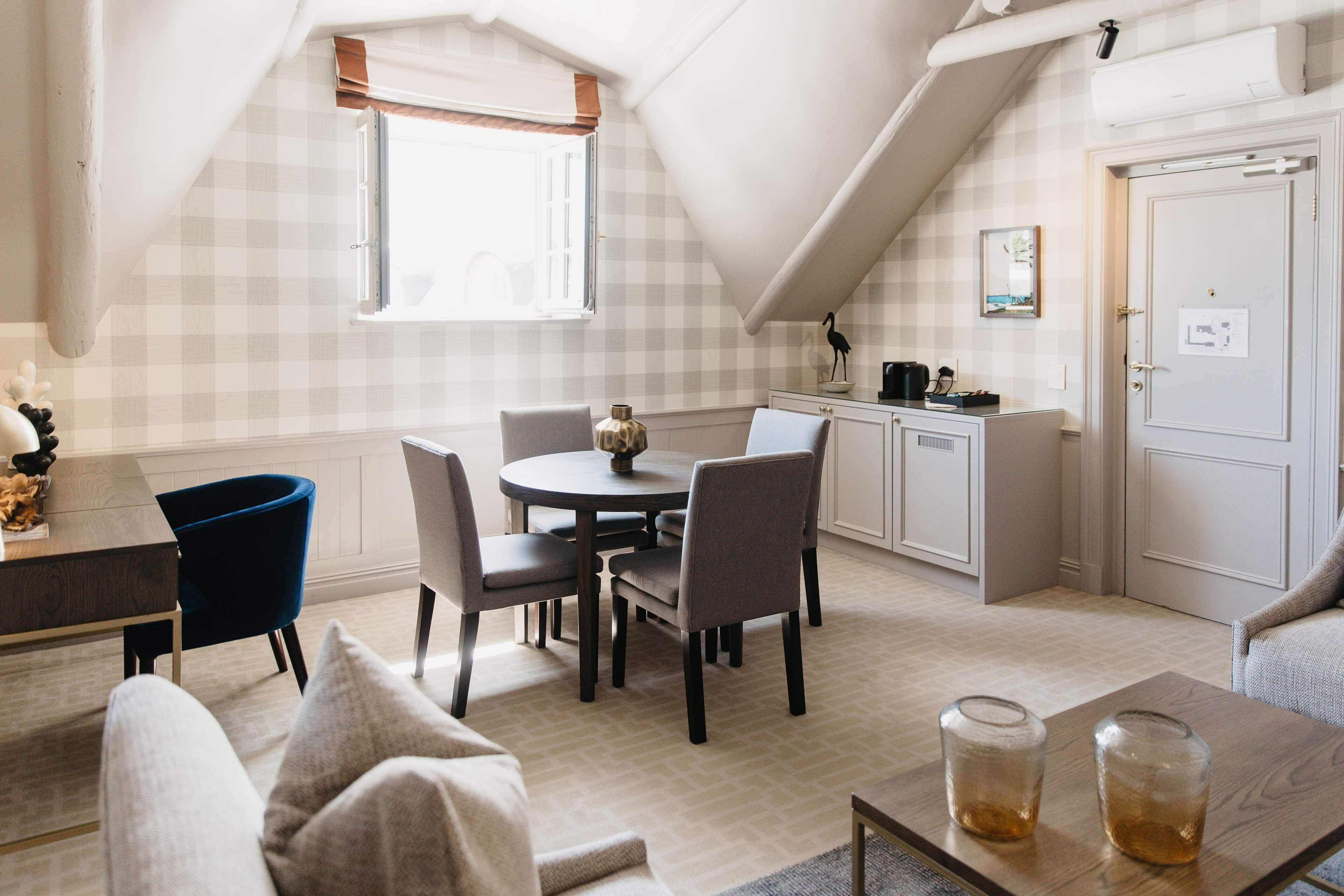 A cozy loft-style room with a dining area, kitchenette, and a large window.