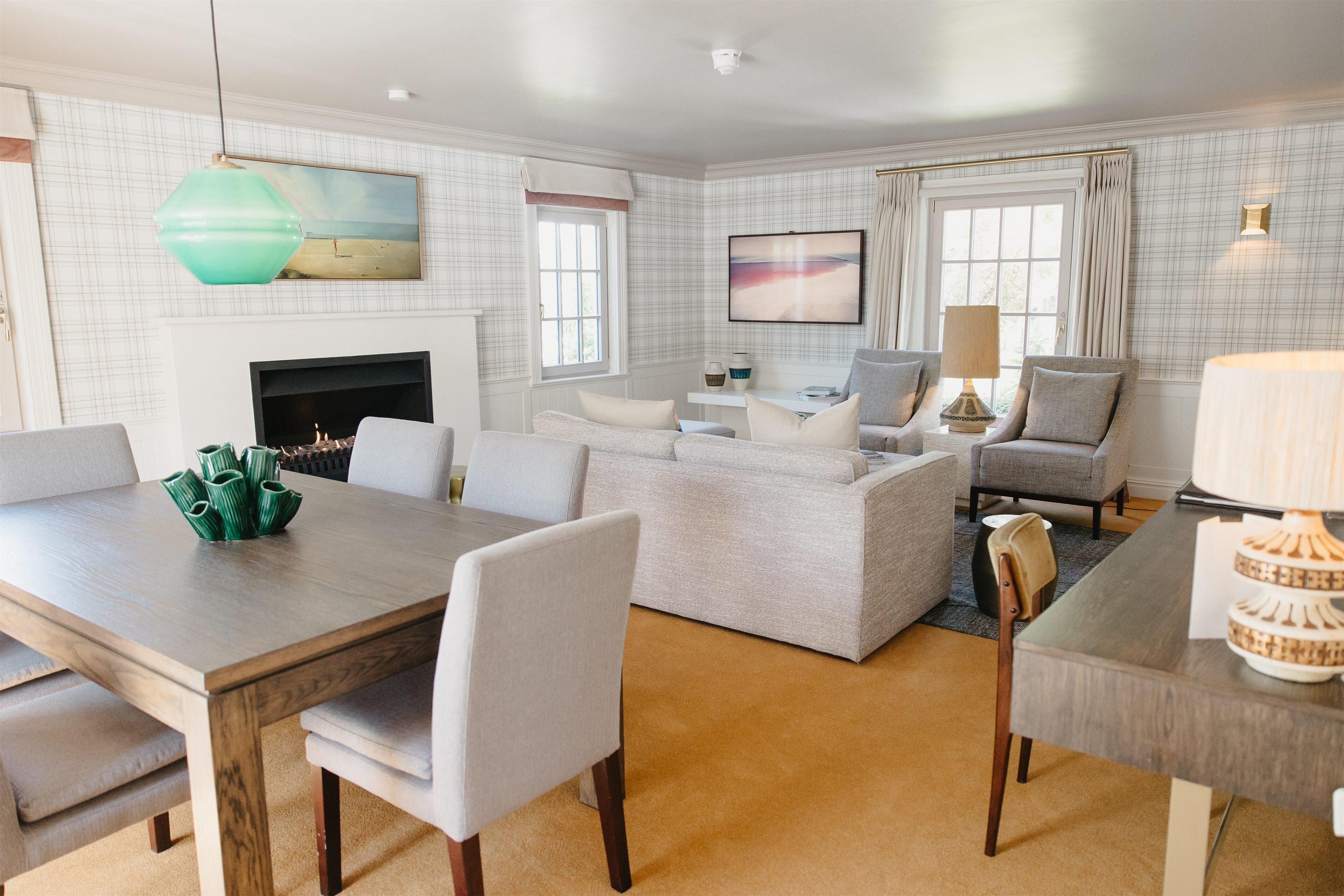 A spacious living room with a fireplace, a large sofa, a dining table, and a TV.