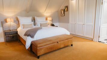 A bedroom with a large bed, bedside lamps, a bench, and a wardrobe.