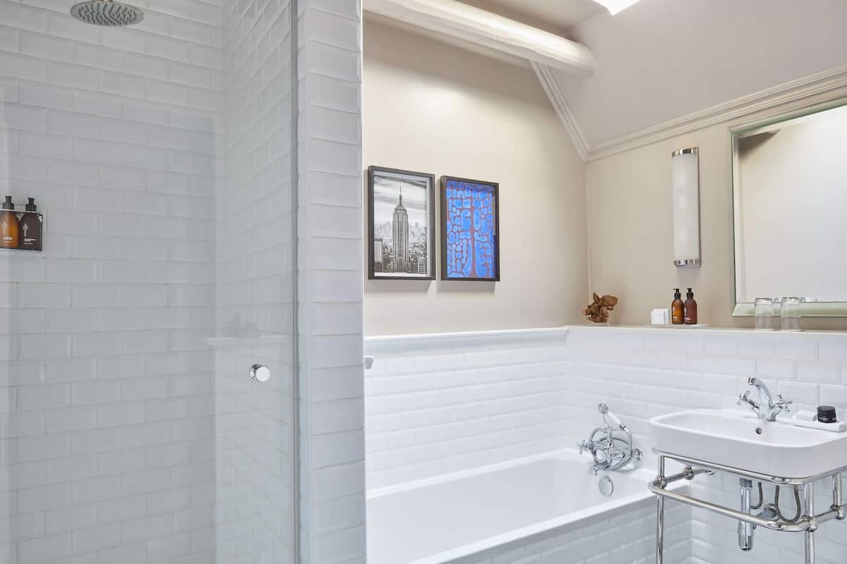 A modern bathroom with white subway tiles, a glass-enclosed shower, a freestanding bathtub, and a large mirror.