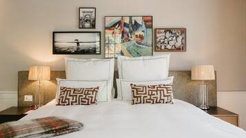 A neatly made bed with patterned pillows, two bedside lamps, and three framed artworks on the wall.
