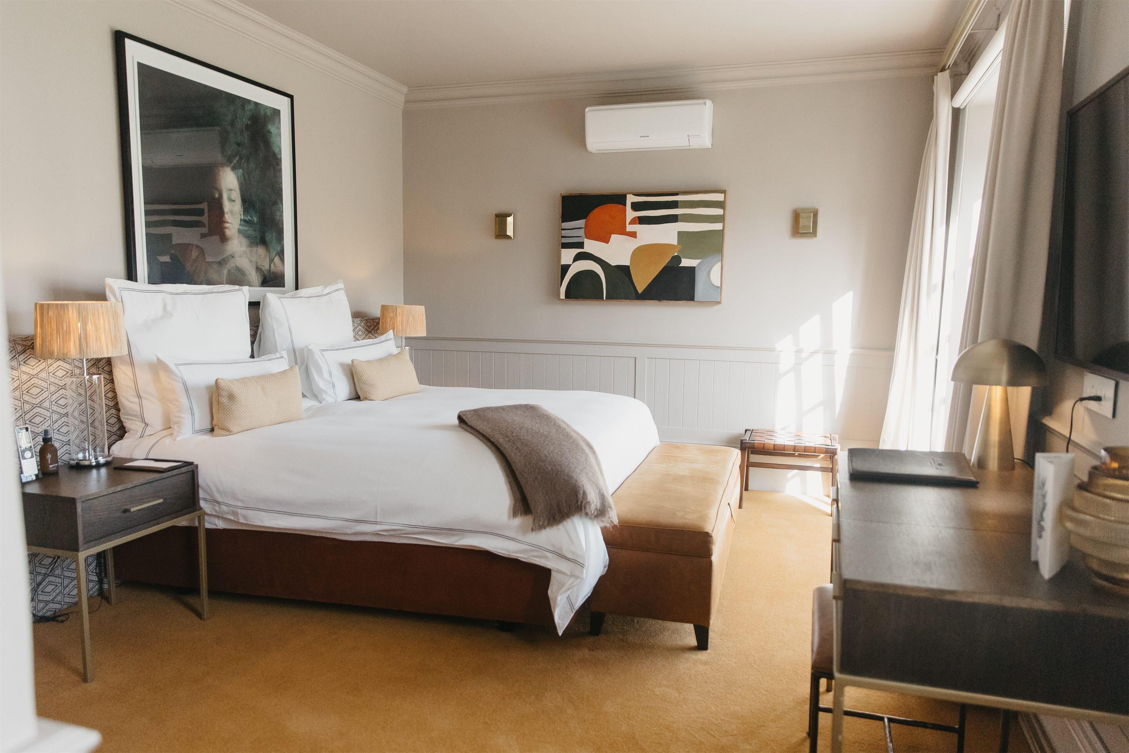 A hotel room with a large bed, bedside tables, a desk, and a TV.