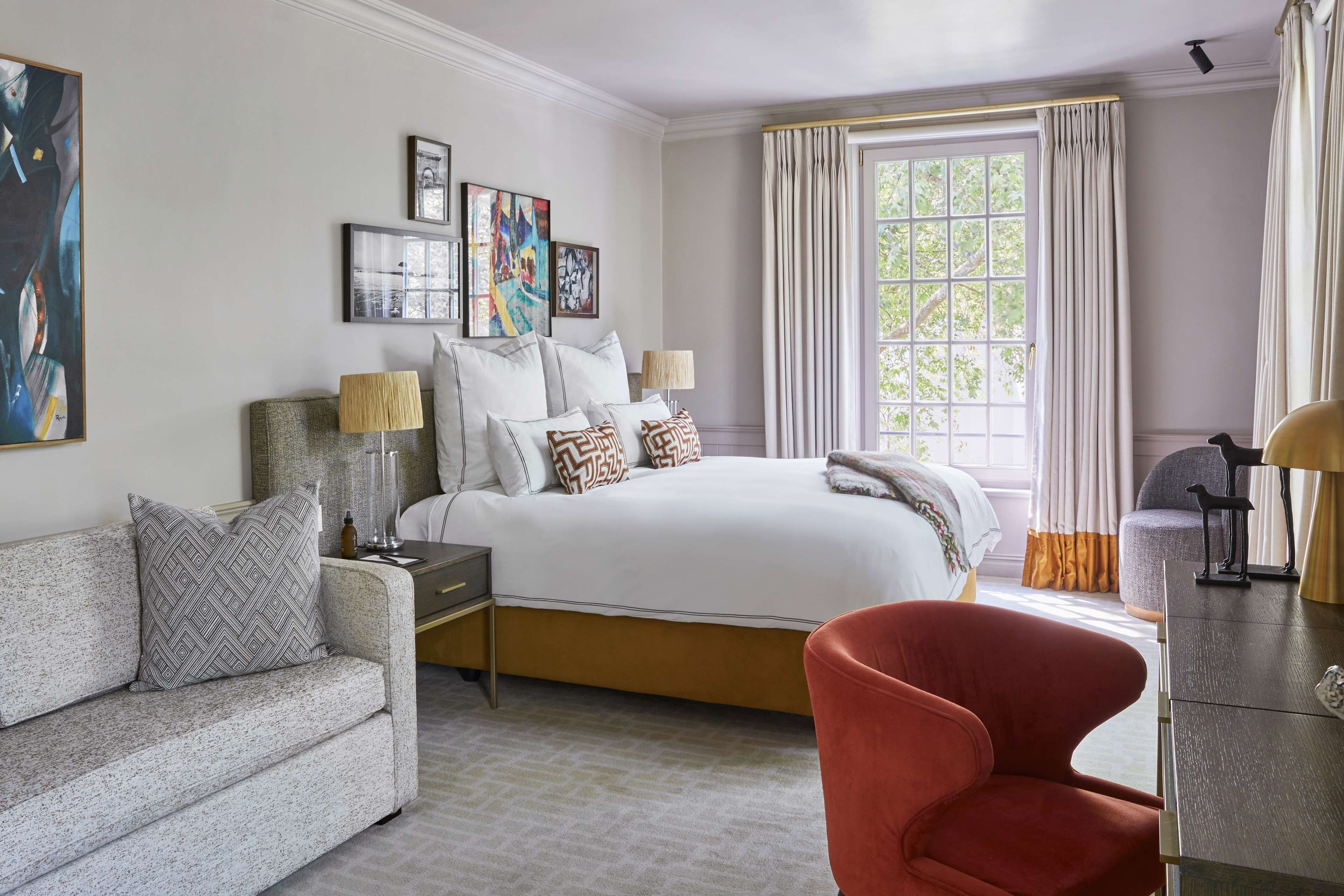 Une chambre à coucher avec un grand lit, un canapé, un fauteuil et une table de chevet avec des lampes.